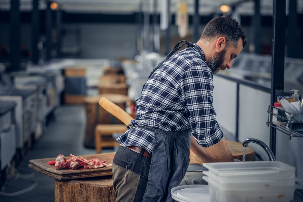 Bearded butcher serving fresh cut meat.